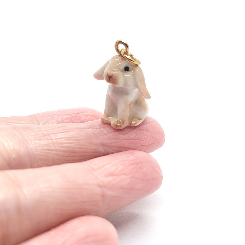 Close up of brown lop rabbit ceramic pendant on finger