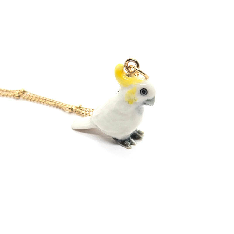 Right side view of a ceramic Yellow-crested cockatoo pendant on a gold-plated stainless steel beaded chain.
