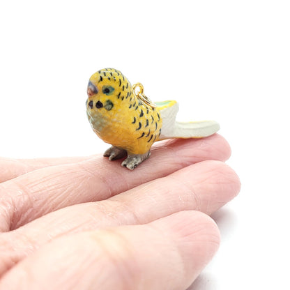 Yellow parakeet pendant on finger