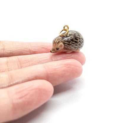 baby hedgehog ceramic pendant on finger