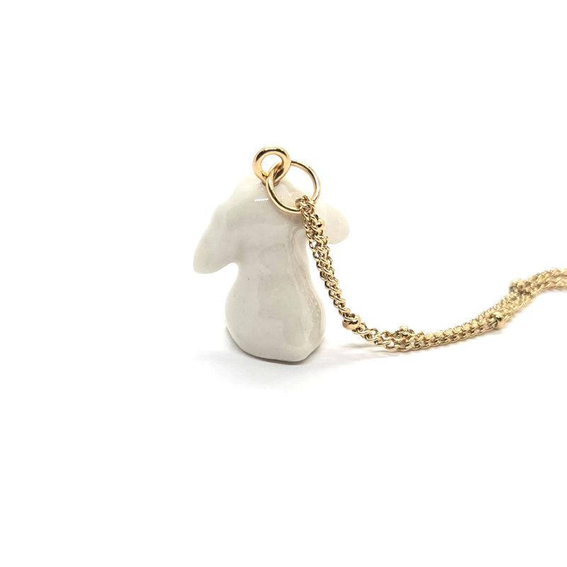 Back view of ceramic white lop rabbit pendant attached to gold-plated beaded chain.