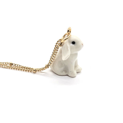 Right side view of ceramic white lop rabbit pendant attached to gold-plated beaded chain.